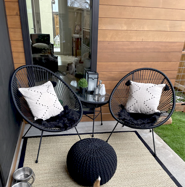A reviewer's image of the black bistro set placed on a cozy small patio.
