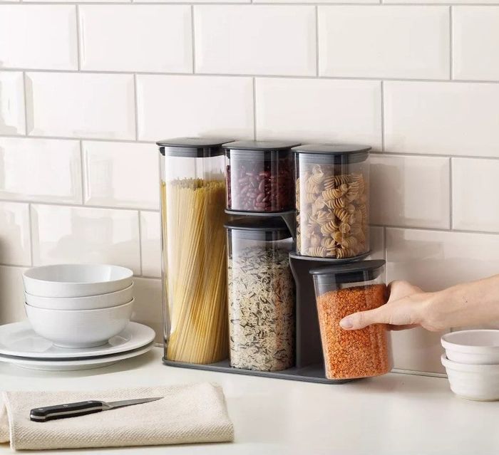 The set of storage containers neatly arranged on their stand on a kitchen counter.