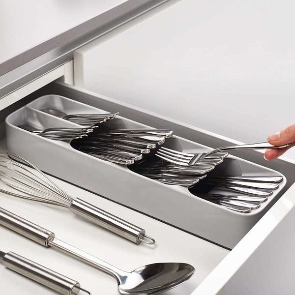 The organizer holding silverware, placed next to other kitchen utensils.
