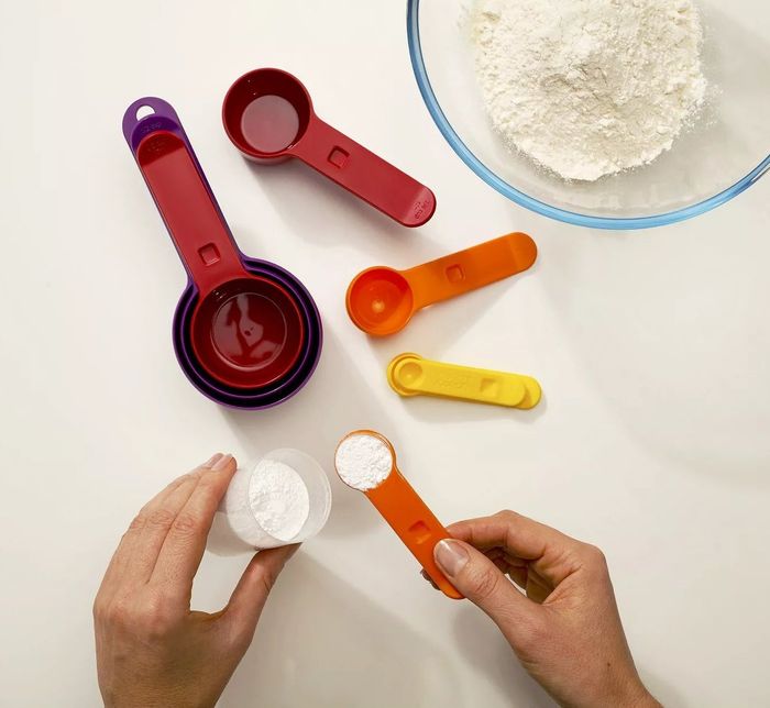 The measuring cups and spoons filled with various baking ingredients.