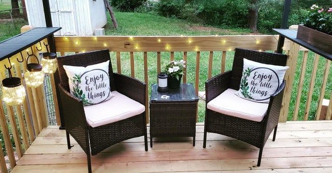 A set of three dark brown rattan chairs accompanied by a matching end table.