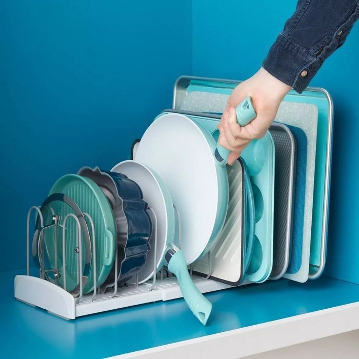 The expandable rack inside a cabinet, neatly organizing pans, lids, and baking sheets.