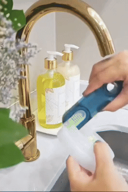 Hands replenishing a soap dispenser at the sink, surrounded by two full soap bottles