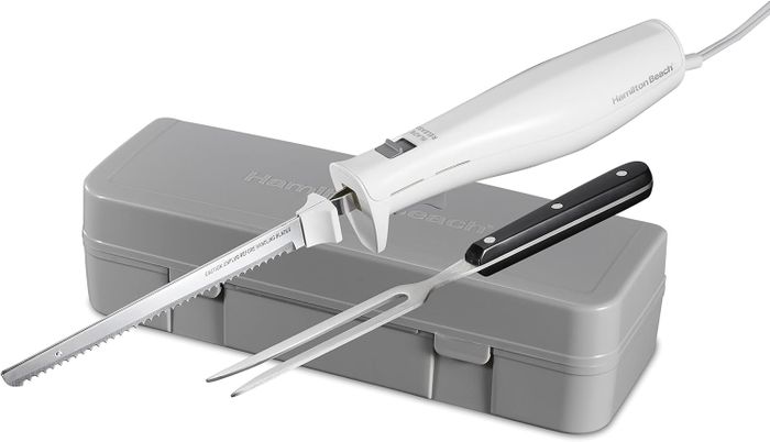 An electric carving knife with a sharp, serrated blade and a sleek black handle, placed next to a carving fork and a practical gray storage case.
