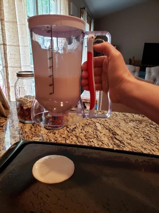 A reviewer using the batter dispenser to pour a flawless circle of pancake batter onto a hot griddle.