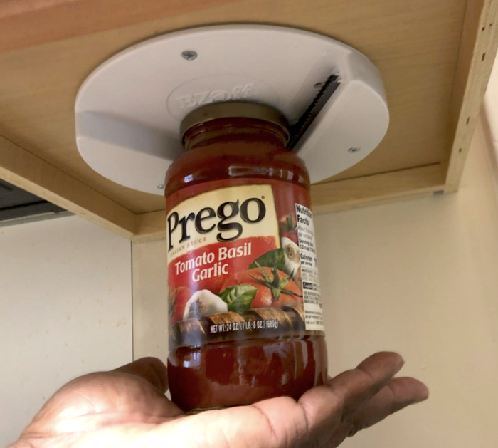A reviewer effortlessly using the opener to unscrew a jar of sauce with just the palm of their hand.