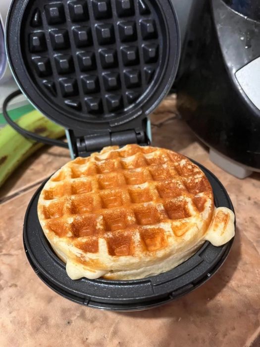 A freshly cooked waffle resting in a waffle maker on a kitchen countertop