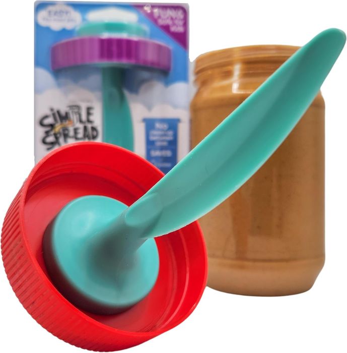 A simple spreading tool with a turquoise handle and red base, resting next to a jar of peanut butter, designed for effortless spreading
