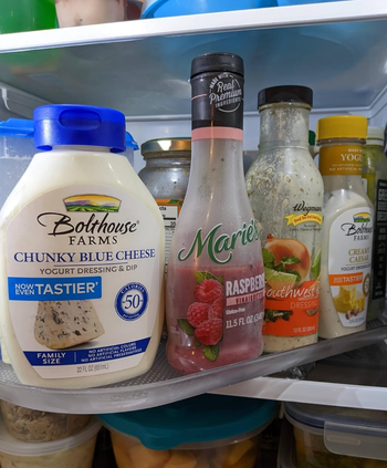 A variety of condiments neatly arranged on a clear plastic turning tray inside a fridge.
