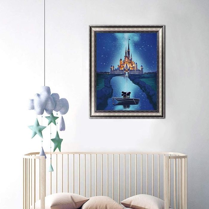 A framed image of Mickey and Minnie on a boat, gazing at the Disney castle under the night sky