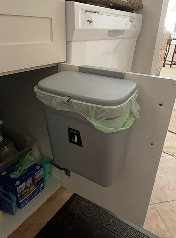 small gray trash bin installed inside a cabinet