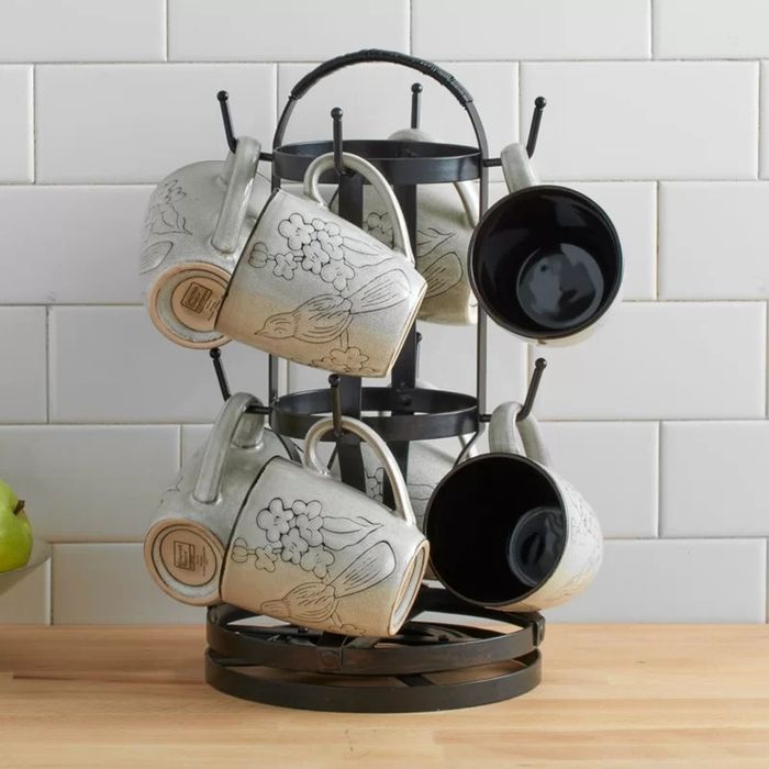 A rotating mug tree filled with mugs, sitting on a kitchen counter.