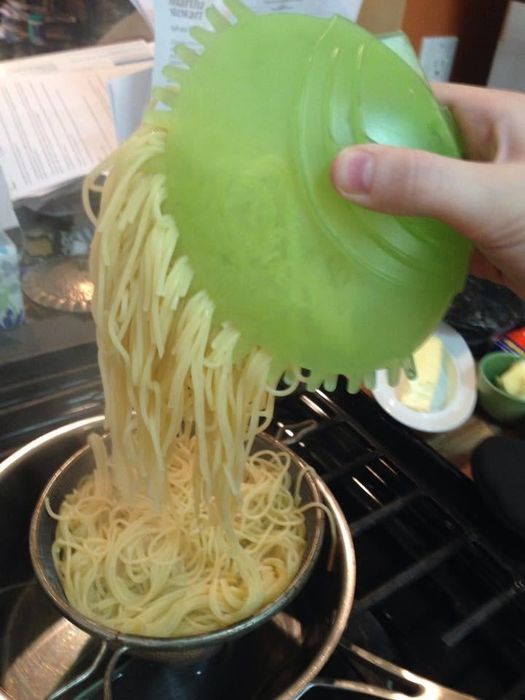 A reviewer's photo showing the green server being used like a mitt to grab pasta directly from the pot.
