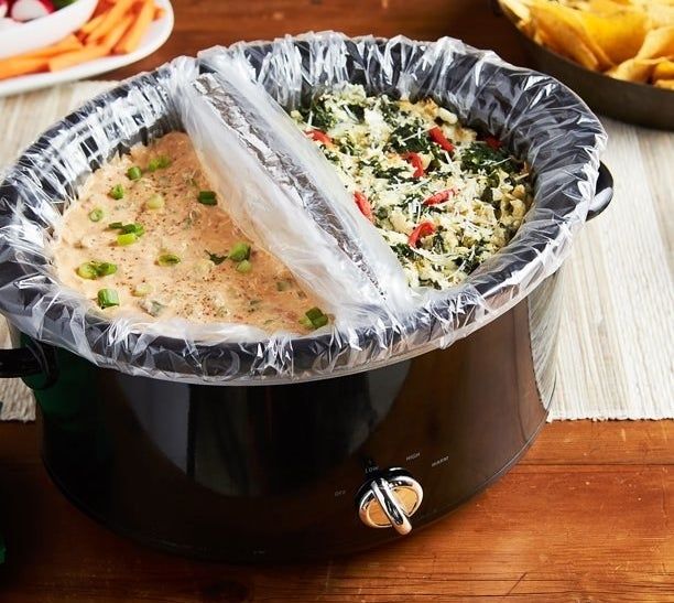 A slow cooker featuring two liners, each filled with a different dish, ready to be cooked.