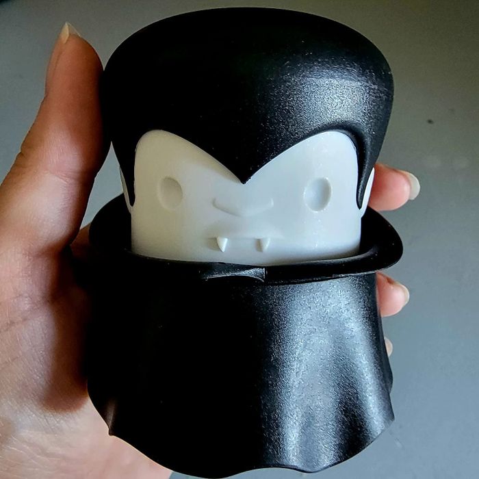 A reviewer holds the vampire-shaped garlic press in their hand.