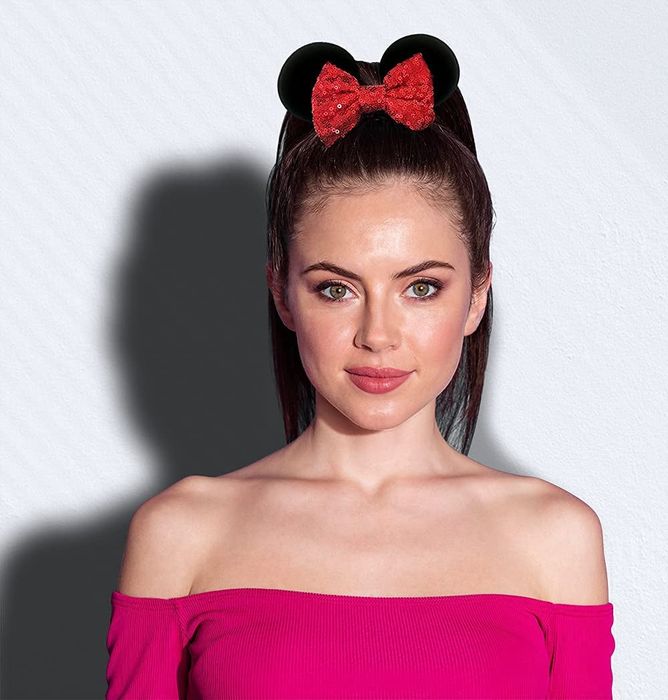 a model sporting a high ponytail with black mouse ears and a red bow