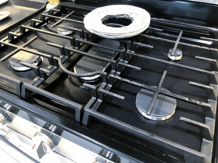 A gas stove featuring five burners, with the central one protected by a metal cover. Ideal for a household kitchen setup.