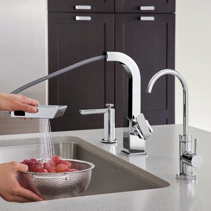 The soap dispenser placed beside a matching faucet in a kitchen.