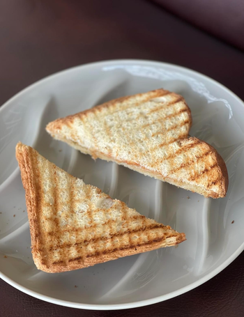 A toasted sandwich, cut into triangles, placed neatly on a white plate with visible grill marks. Perfect for a food-themed shopping article