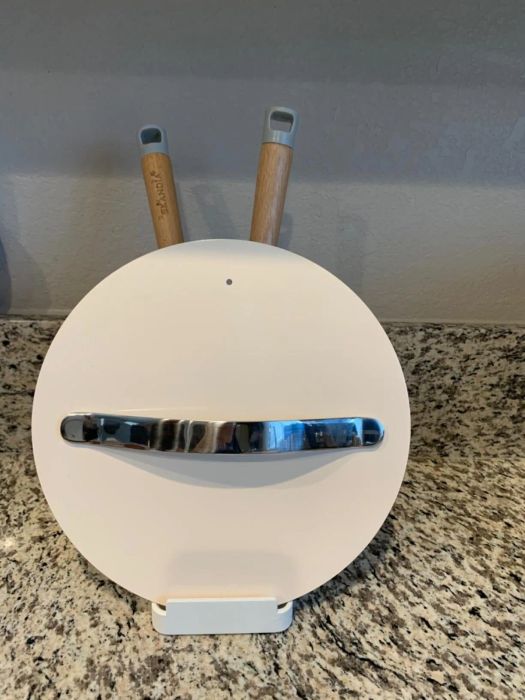 The utensil holder with a couple of utensils and a pot lid resting inside it