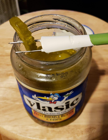 A reviewer using the three-pronged fork to pick up a pickle