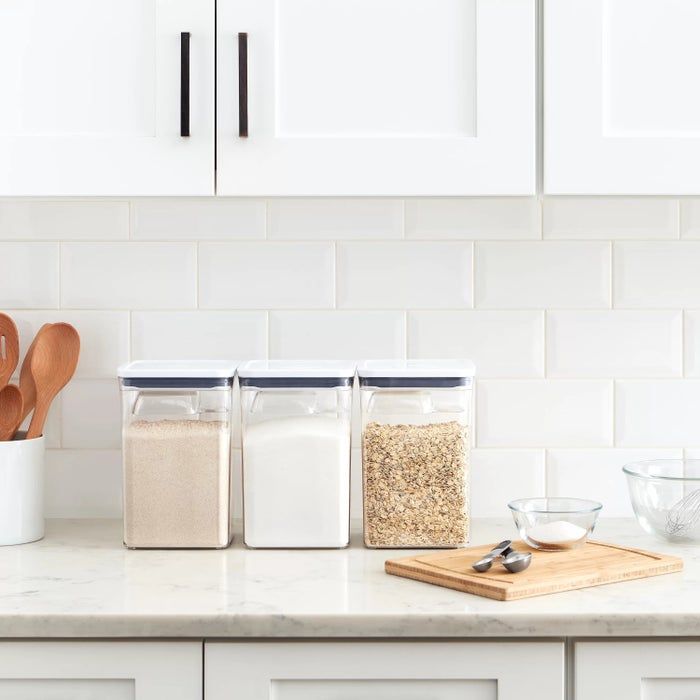 The storage containers neatly arranged with sugar, flour, and oats on a kitchen counter