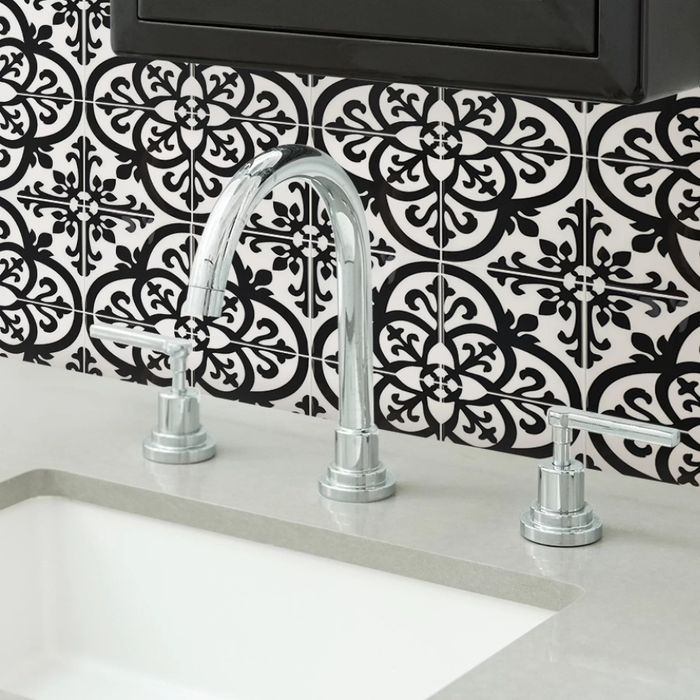 The peel-and-stick black and white mosaic tiles placed behind a bathroom sink.
