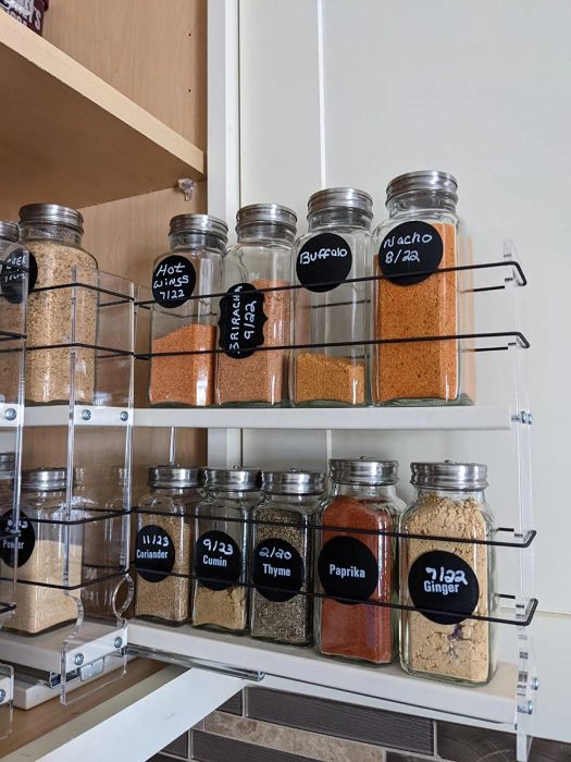 The same reviewer pulls out one of the racks, with its flexible sides holding spice bottles securely in place
