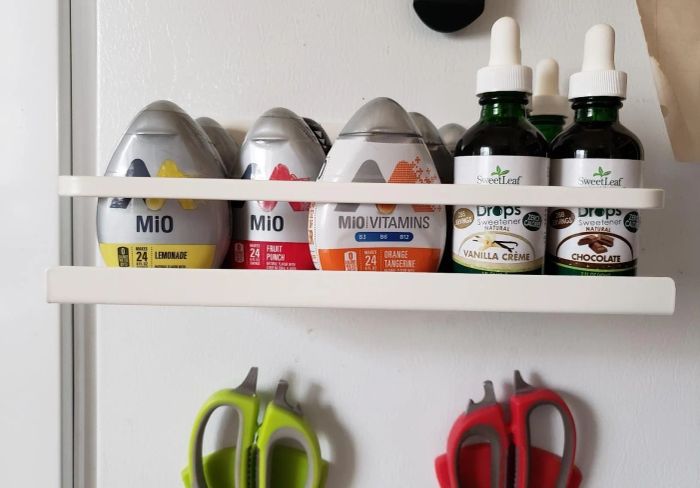 Flavor enhancers and sweetener drops on a shelf with scissors hanging underneath