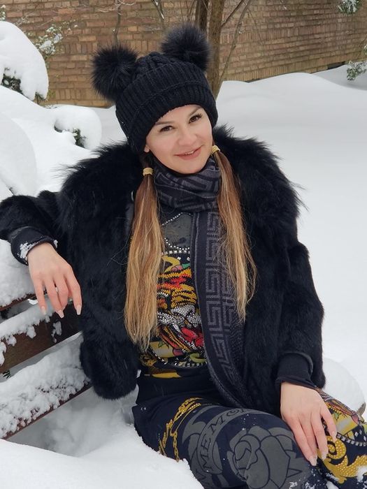 A reviewer wearing a black beanie with two Mickey-inspired pom-poms on top