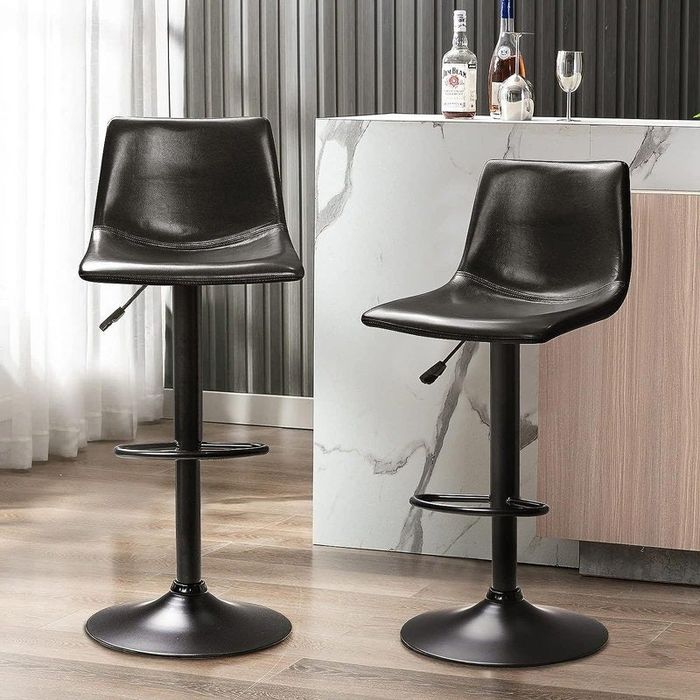 Two sleek black bar stools with footrests and adjustable height, positioned by a marble counter.