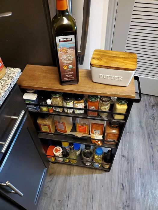 A kitchen spice rack displaying a variety of spices, a bottle of extra virgin olive oil, and a butter dish resting on top