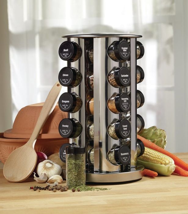 A rotating metal spice rack with transparent jars featuring black-labeled lids, arranged in five rows