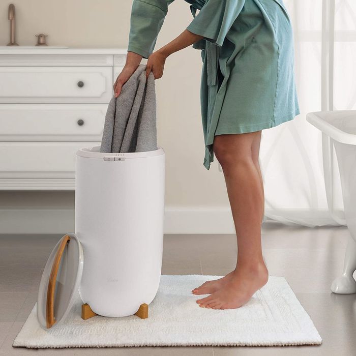 A person removing a towel from the Zadro towel warmer
