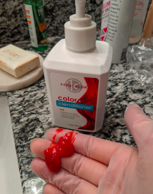 A customer review photo featuring a bottle of Keracolor Clenditioner in red with several pumps on their gloved hand.