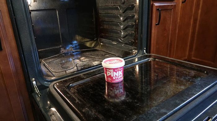 A photo of The Pink Stuff sitting in front of a dirty oven, ready to tackle the mess.