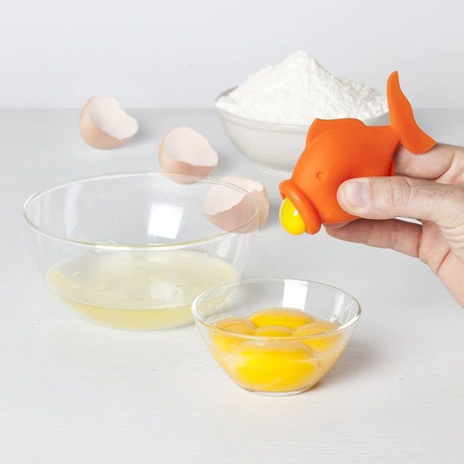 a fish-shaped orange tool extracting the yolk from an egg
