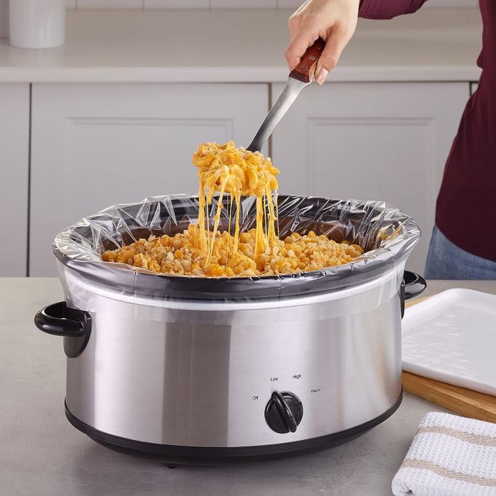 A model scooping mac and cheese from a lined Crock-Pot