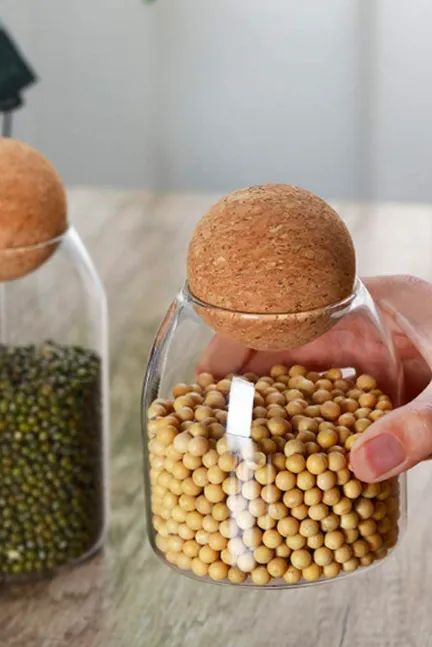 Person holding a small glass jar with a round cork lid