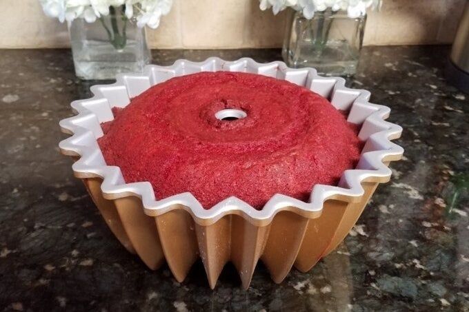 A Bundt cake in its pan on a counter with white flower bouquets in the background. Shopping category
