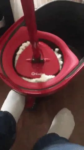 A reviewer using the foot-operated pedal to wring out the microfiber mop.