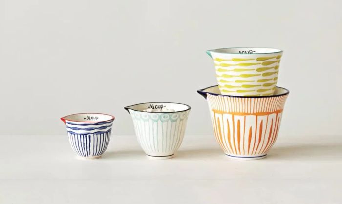Four stacked ceramic measuring cups featuring a variety of designs, ready for purchase