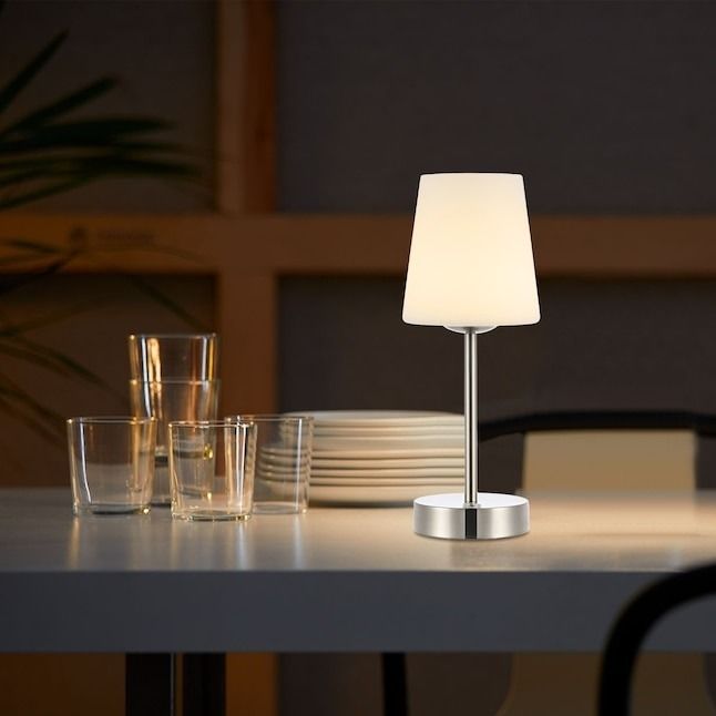 A contemporary table lamp with a white shade placed on a table