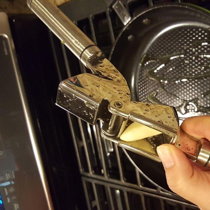 A garlic clove being placed inside the garlic press