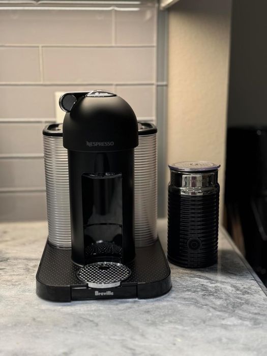 A Nespresso coffee machine with an attached milk frother sitting on a kitchen counter