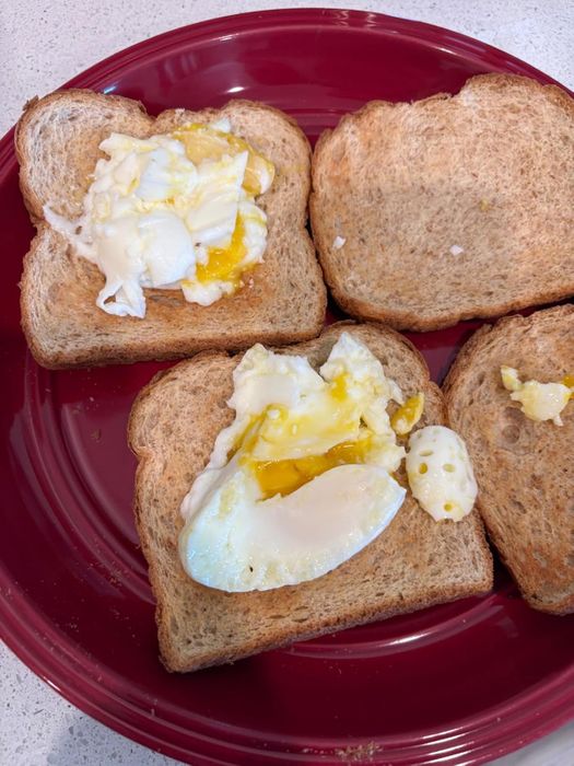 three slices of toast topped with perfectly fried eggs, served on a vibrant red plate