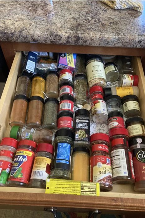 A reviewer's before photo of an unorganized and cluttered drawer filled with spice jars.