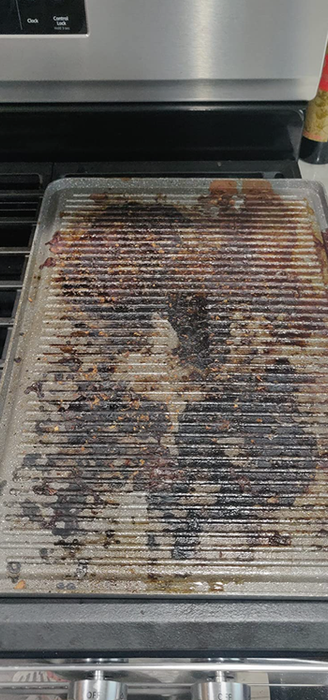 A reviewer's grill covered in burnt-on grease