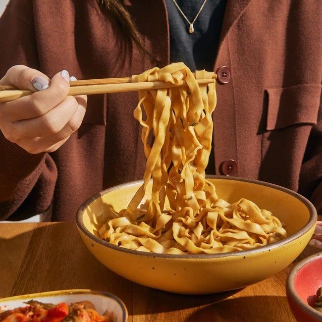 A person enjoying noodles from a bowl