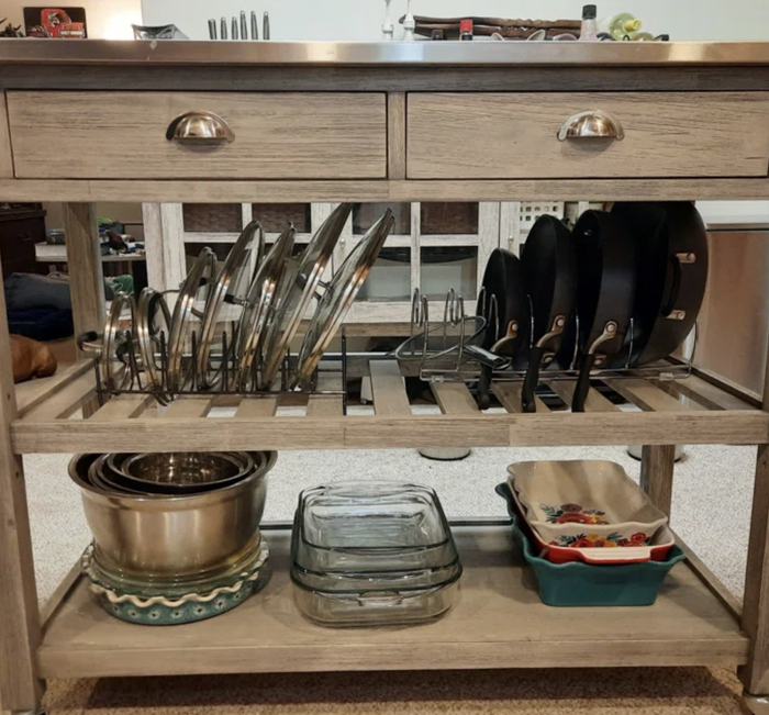 A kitchen cart neatly organized with pots, lids, pans, and baking dishes, offering a smart and efficient storage solution for your kitchen essentials